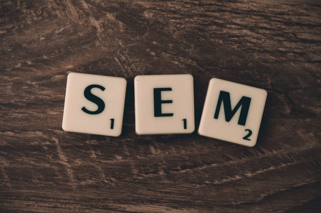 About Wooden background with letter tiles spelling SEM, representing search engine marketing.